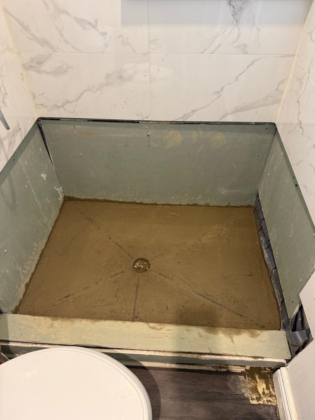 Shower walls tiled in large-format marble-look porcelain