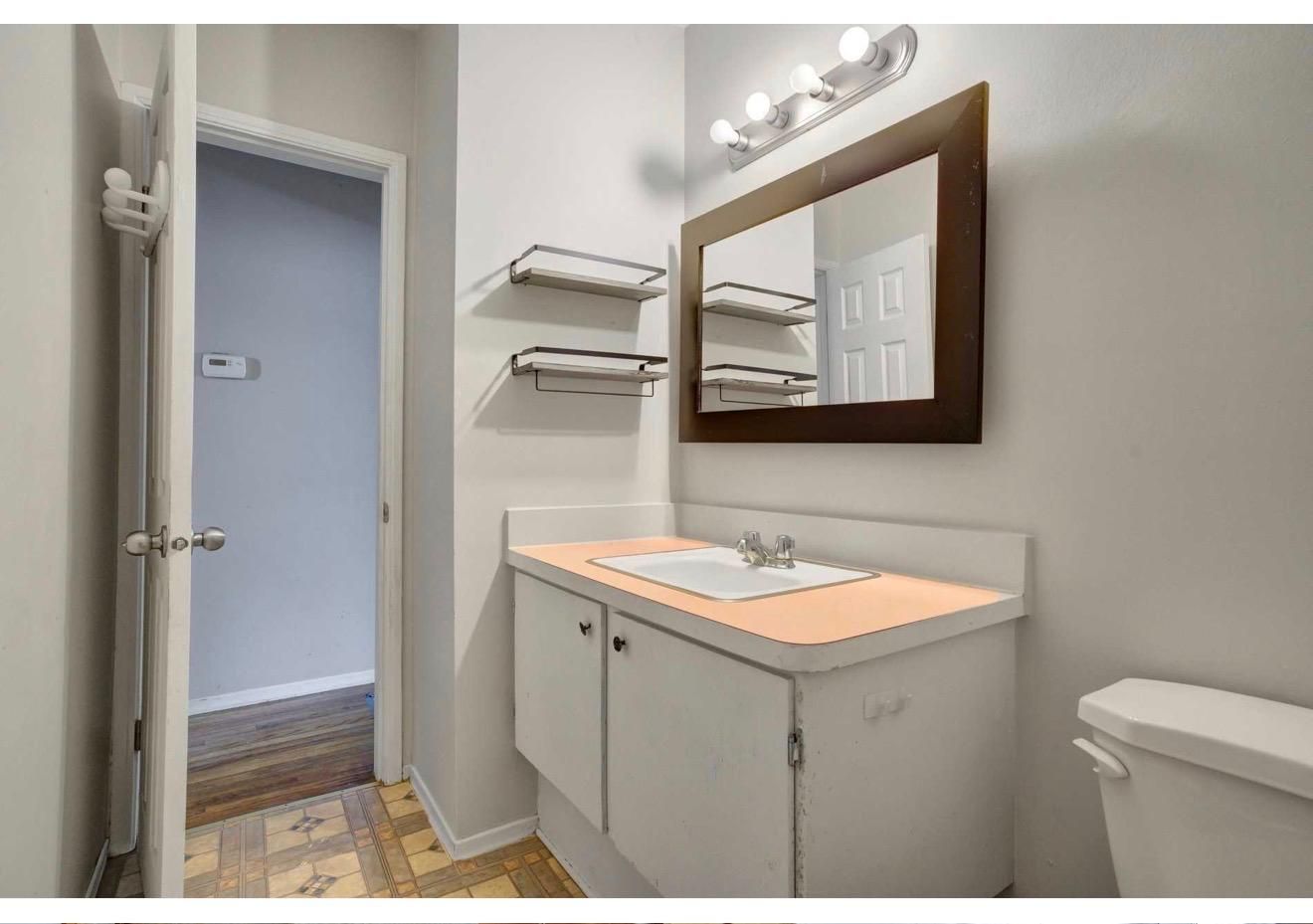Renovated bathroom with a new vanity, mirror and wall shelving